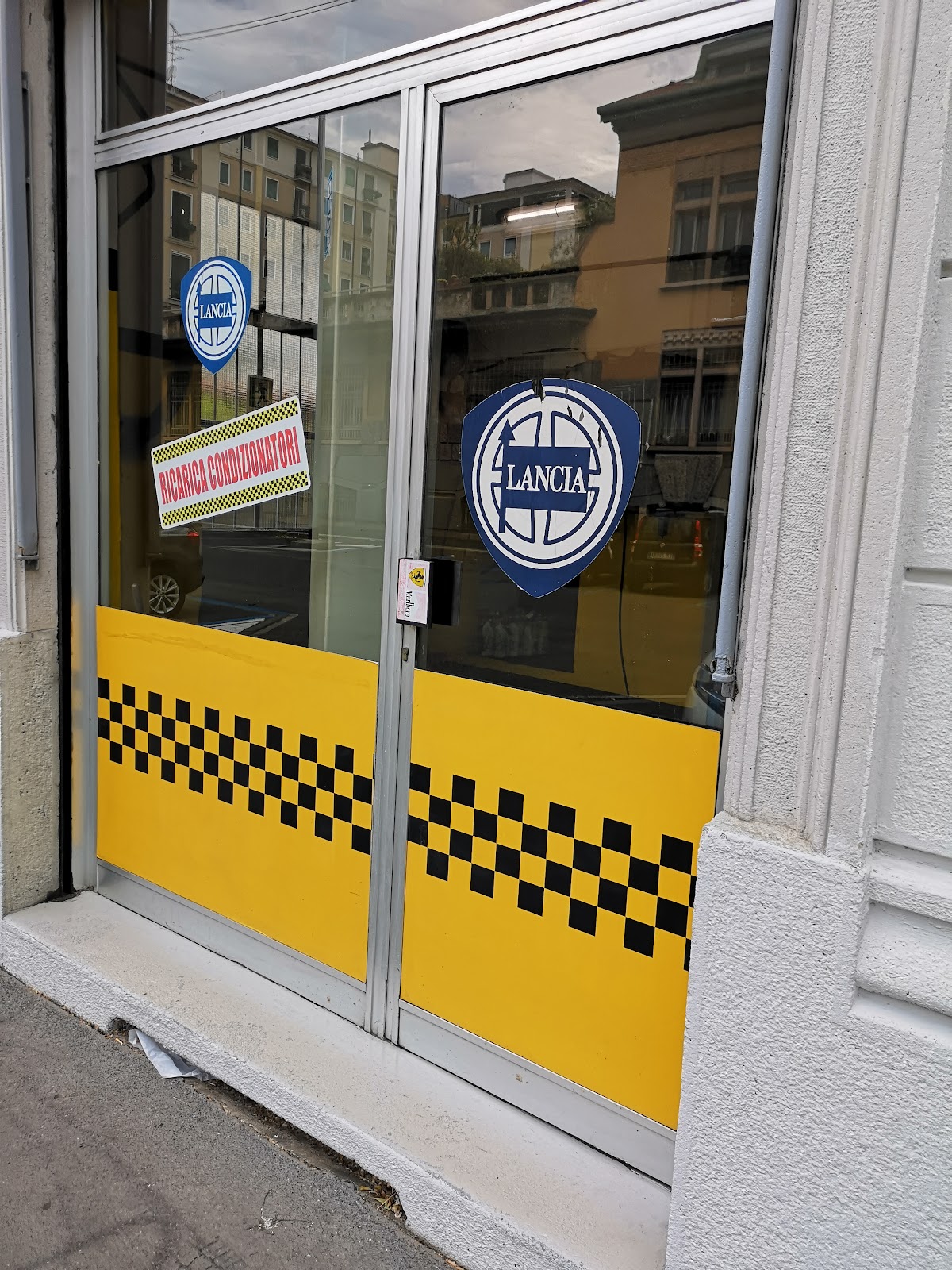 Vista facciata officina con bandiera a scacchi e insegna gialla